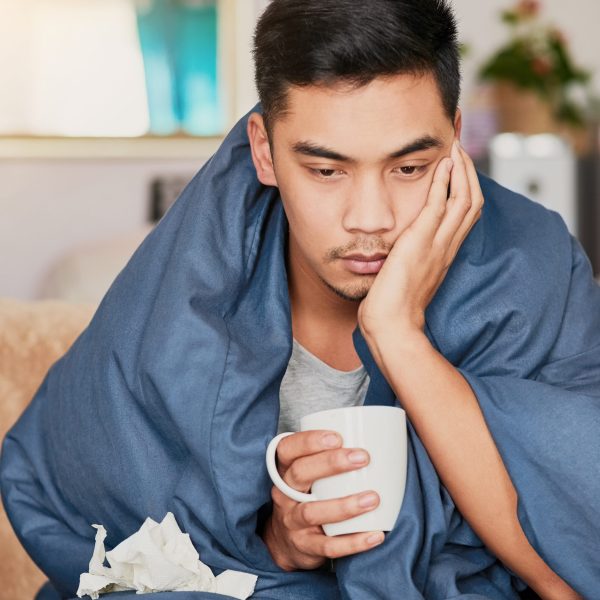 Nothing fun about the flu. Shot of a young man with a cold recuperating at home