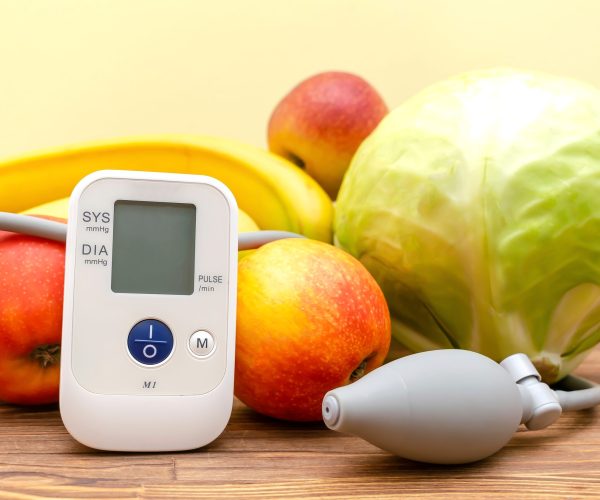 Tonometer and glucose meter,bunch of fresh vegetables,fruits, proper nutrition, healthy lifestyle, lowering blood sugar, heart pressure, diabetes concept on yellow,wooden background.